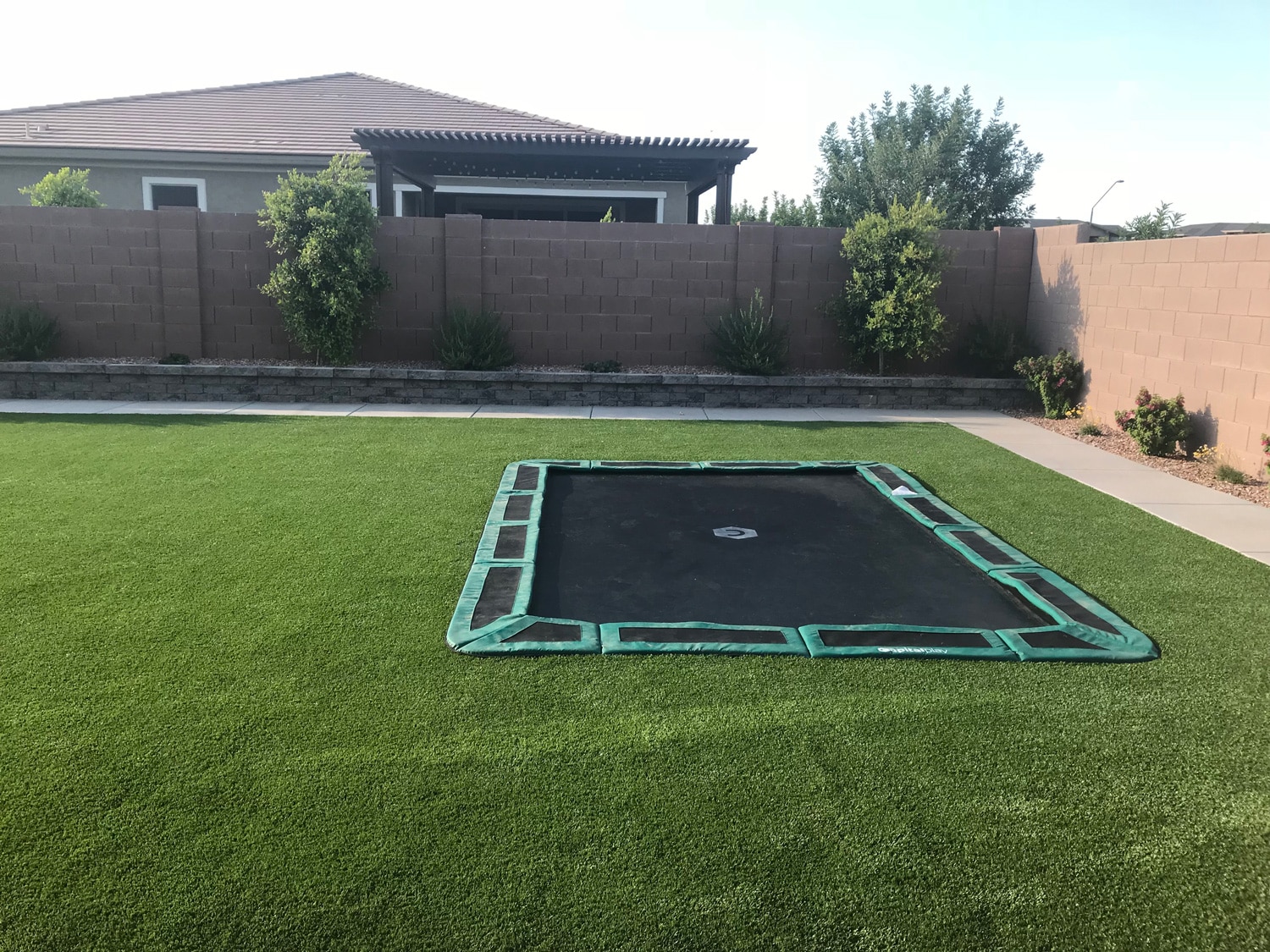 Patio green in-ground trampoline completed by Capital Play