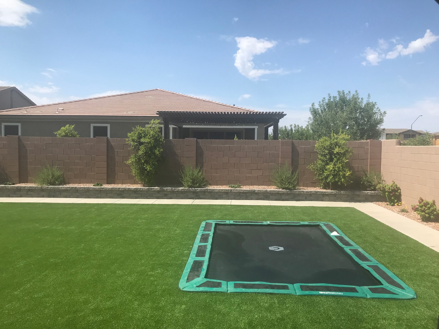 Rear view of backyard in-ground trampoline installed