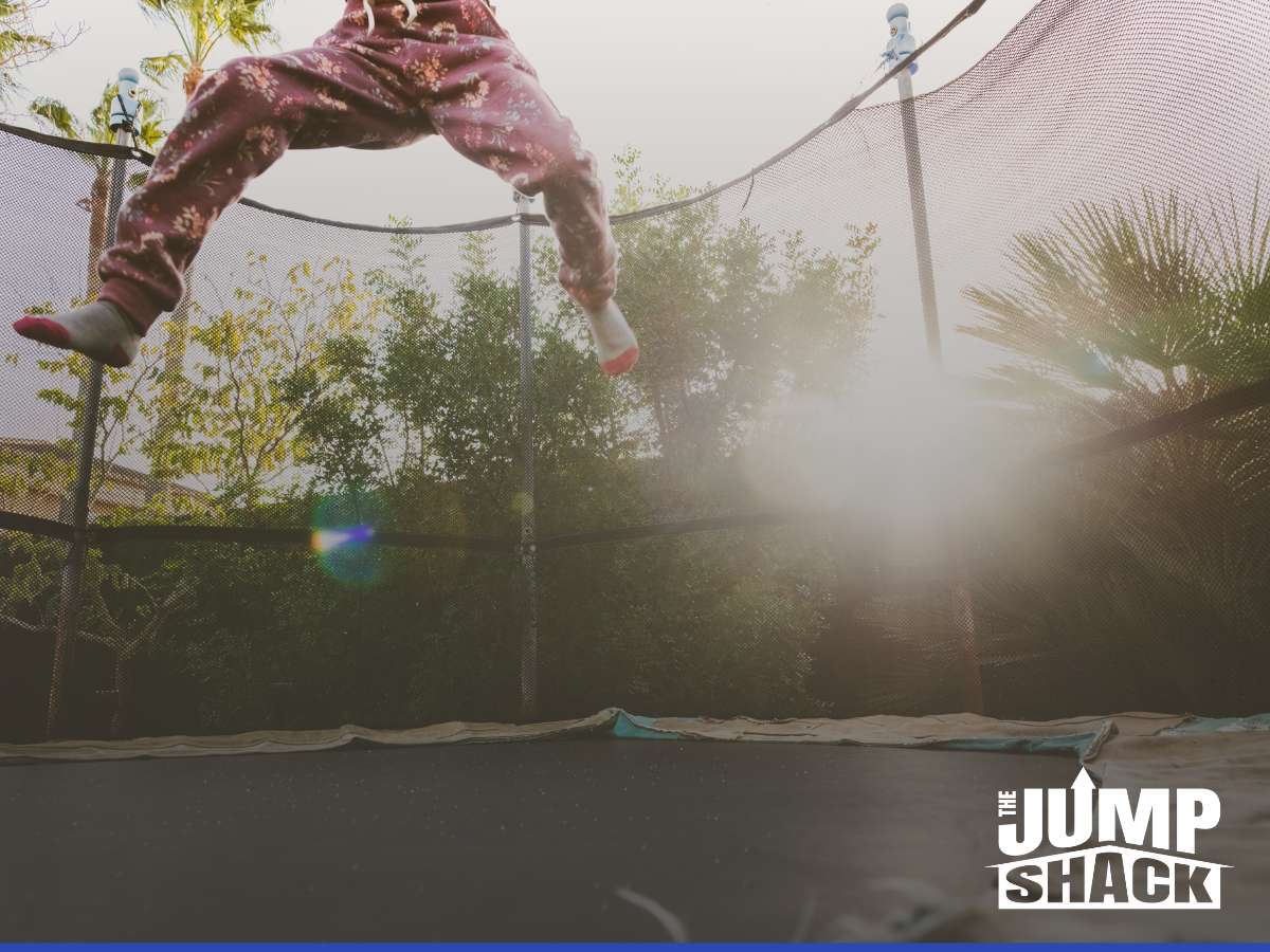 Child jumping high on an In-Ground Trampoline in a backyard surrounded by trees and sunlight