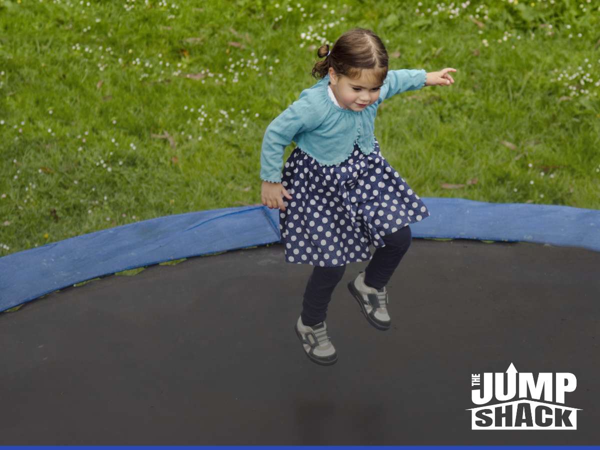 Young girl joyfully jumping on an in-ground trampoline, showcasing the need to regularly replace the nets & enclosures for safety