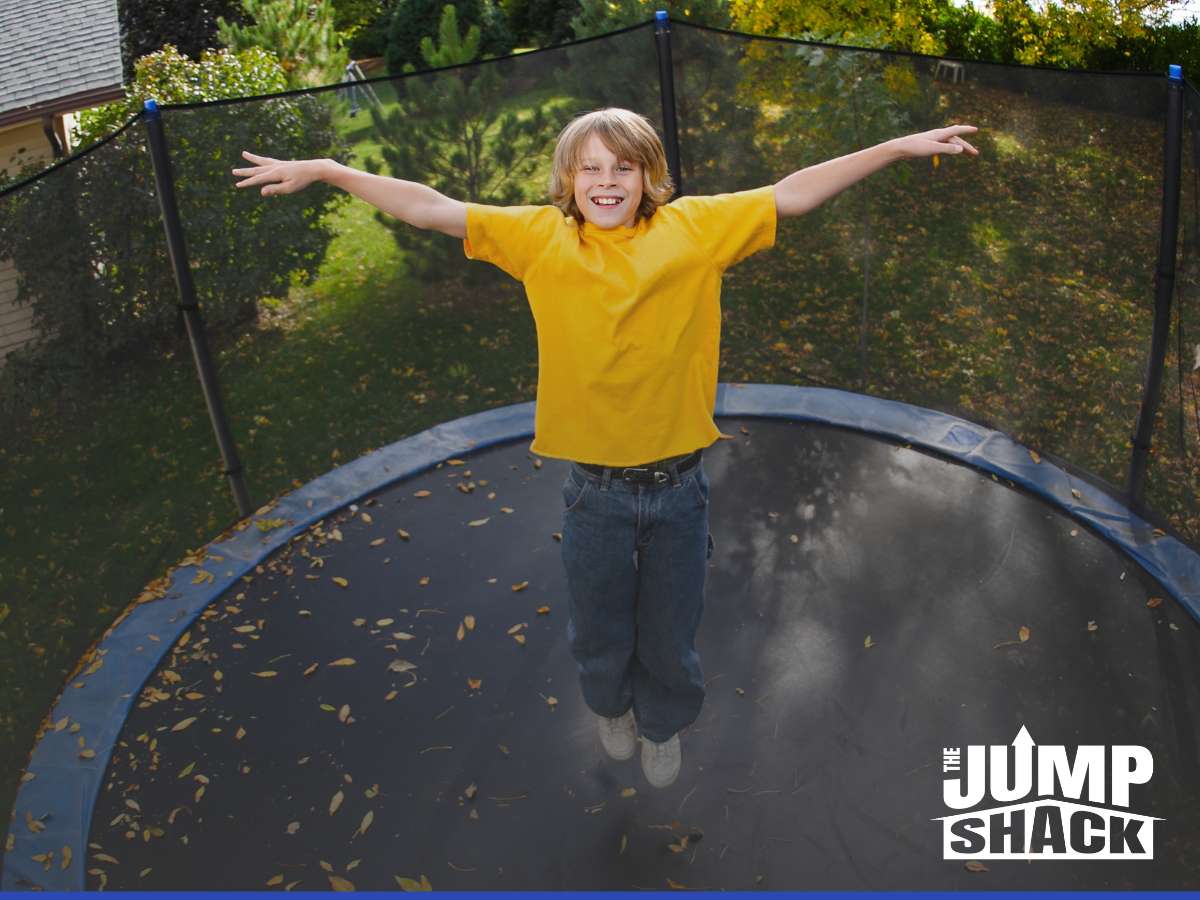 Boy happily bouncing on an in-ground trampoline installation in a backyard