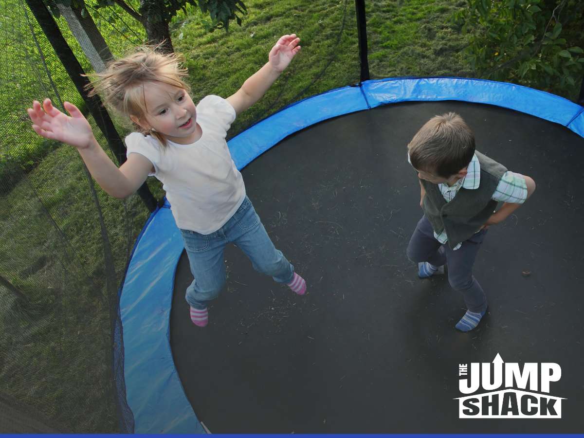 Kids playing on an in-ground trampoline in a backyard